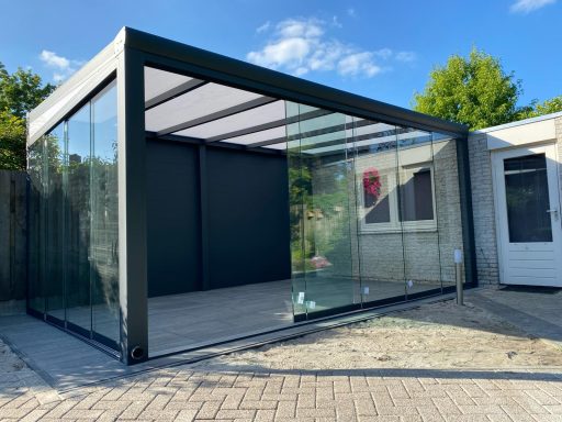Moderne glazen veranda met een metalen frame en een zonnige omgeving.