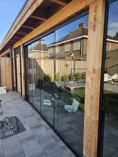 Moderne glazen schuifdeuren met houten omlijsting en uitzicht op een tuin.