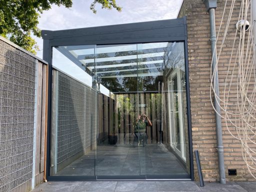 Moderne serre met glazen wanden, verbonden met een bakstenen muur.