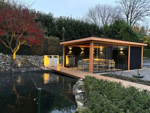 Moderne houten overkapping naast een vijver, omringd door bomen en struiken.