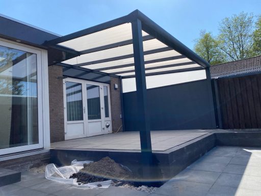 Moderne overkapping met zwart frame en houten terras achter een woning.