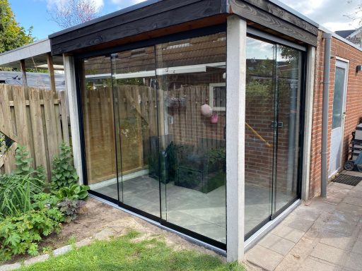 Moderne glazen veranda met een houten omheining en een betegeld pad.